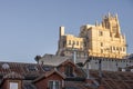 City rooftops with metal chimneys and industrial smoke vents and stately building facades bathed in morning sunbeams