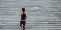 City run. Slim muscular girl in bright athletic uniform runs up the stairs