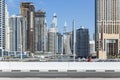 City scape with modern high-rise buildings, street and with man walking in walk way and blue sky in background at Dubai