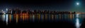 A city skyline lit up at night with a full moon in the sky, AI Royalty Free Stock Photo