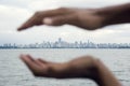 City Skyline Seen Across Water w/ Cupped Hands