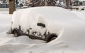 City street after blizzard. Stuck cars under the snow and ice. Buried vehicle in snowdrift on the road. Parking lots in