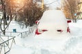 City street driveway parking lot spot with small car covered snow stuck trapped after heavy blizzard snowfall winter day Royalty Free Stock Photo