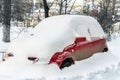 City street driveway parking lot spot with small car covered snow stuck trapped after heavy blizzard snowfall winter day Royalty Free Stock Photo