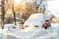 City street driveway parking lot spot with small car covered snow stuck trapped after heavy blizzard snowfall winter day Royalty Free Stock Photo