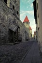 City street of the old city in Tallinn with an ancient wall of limestone and red tile roofs on the towers. Royalty Free Stock Photo