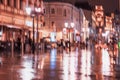 City street in rainy late evening, abstract background of blurred people figures under umbrellas, orange brown tones Royalty Free Stock Photo