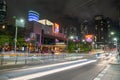 City street scene in long exposure with blurred shapes and colours of passing vehicles and people against illuminated buildings Royalty Free Stock Photo