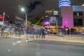 City street scene in long exposure with blurred shapes and colours of passing vehicles and people against illuminated buildings Royalty Free Stock Photo