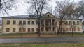 On a city street stands an old plastered brick two-story house with columns and a metal balcony. Some of the windows are boarded u Royalty Free Stock Photo