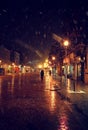 City street at winter snowy night with people walking. Blurred city lights. Snowfall. Royalty Free Stock Photo