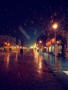City street at winter snowy night with people walking. Blurred city lights. Snowfall. Royalty Free Stock Photo
