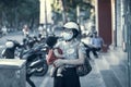 On the city street, a young mother with a baby in her arms masked on her face, the concept of the spread of the coronavirus from