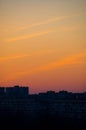 A city sunset, four cirrus oblong clouds over dark blue houses