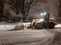 Service snow plowing truck cleaning residential street during heavy snowstorm, Toronto, Ontario, Canada.