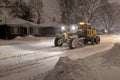 Service snow plowing truck cleaning residential street during heavy snowstorm, Toronto, Ontario, Canada.