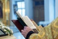 The hands of an Orthodox priest, a cross and a prayer book.