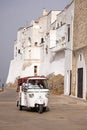 City wall of Ostuni with Vespa scooter on the road.