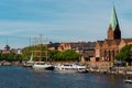 Cityscape of Bremen with old architecture, historical wooden sailing ships and barge floating along the river Weser