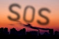 Cityscape with dramatic sky sunset. Silhouette of buildings and smoking pipes. Urban industrial city. SOS text made of emission s Royalty Free Stock Photo