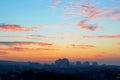 Cityscape in the early morning: pink and orange clouds on a blue sky at dawn just before sunrise over the sleeping city