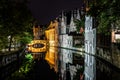 A cityscape with a lot of buildings reflected in the lake at night in Bruges, Belgium