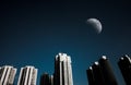 Cityscape at night time and darkness sky with half moon