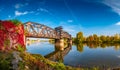 Cityscape of old railway metal rusty bridge in red ivy leaves over Elbe river in downtown of Magdeburg in Autumn colors, Germany