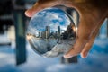 Cityscape photography in a clear glass crystal ball with dramatic clouds sky.