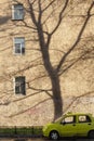 Cityscape with shadow from a tree on the wall. small yellow car on the background of a large house Royalty Free Stock Photo