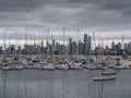 Cityscape shows a bustling marina with a variety of boats of varying sizes, colors, and types