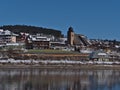 Cityscape of Schluchsee with snow-covered church St. Nikolaus, train station and hotels reflected in frozen lake in winter season. Royalty Free Stock Photo