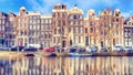 Cityscape on a sunny winter day - view of the houses and the city channel with boats in the historic center of Amsterdam