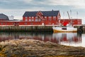 Cityscape of the town Henningsvaer, whaling and whaler boat, rocky coast with dramatic sky, classic view of Norwegian