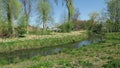 Cityscape of town Wittstock Dosse in Germany. People walking through small park with stream flowing. Tulip blossom in springtime.