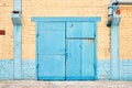 Cityscape. Urban symmetric view of abandoned factory building blue painted rusty gate on yellow brick wall with