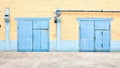 Cityscape. Urban symmetric view of abandoned factory building blue painted two rusty gates on yellow brick wall with
