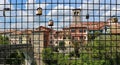 Lovers padlocks on a wire mesh with che cityscape of the town center on background.