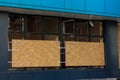 Civil building damaged by military drones attack. Windows with broken glass covered with OSB boards. Repairing after war