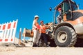 Civil engineer and worker discussion on road construction site Royalty Free Stock Photo