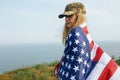 Civilian woman in her husband`s military cap. A widow with a flag of the united states left without her husband. Memorial Day to