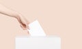 Civilized Equal Rights Concept. Female Hand Lowers Ballot In Ballot Box On Light Suntan Peach Background Royalty Free Stock Photo