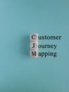 CJM customer journey mapping symbol. Concept words CJM customer journey mapping on wooden cubes on a beautiful blue backgro