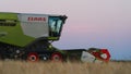 CLAAS combine harvester on a hill at sunset.