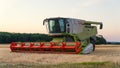 CLAAS combine harvester on a hill at sunset.