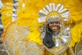 Clad in a bright yellow and gold masquerade a young smiling woman enjoys the Children`s Carnival parade in St James Trinidad