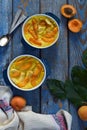 Clafouti with apricots in rameken on blue wooden background. Fruits clafoutis. Sweet casserole. Traditional French cake. Copy spac