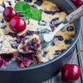 Clafoutis with cherry in baking dish, on wooden table, square format, closeup Royalty Free Stock Photo
