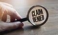 Claim denied in a magnifying glass on a wooden table. Insurance business concept Royalty Free Stock Photo