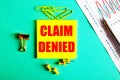 CLAIM DENIED is written in red on a yellow sticker on a green background near the graph and pencil Royalty Free Stock Photo